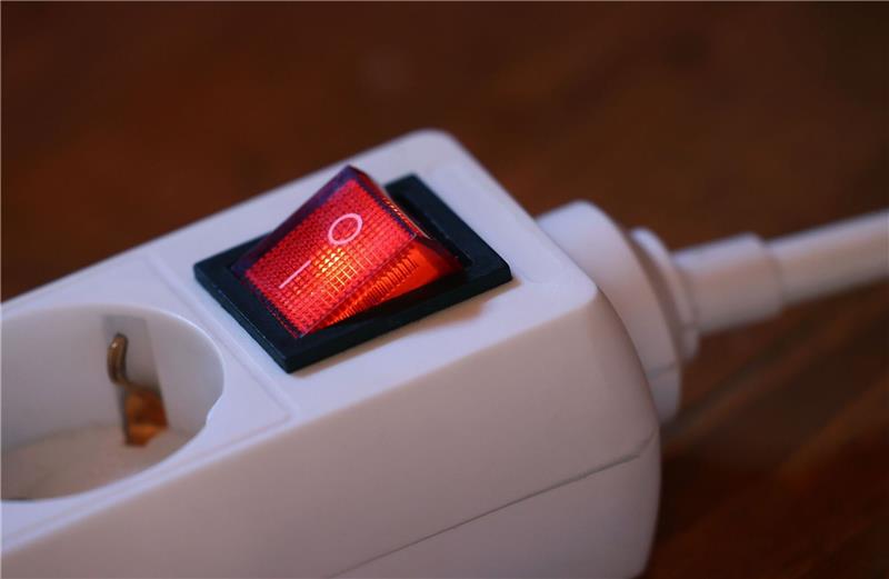 Der eingeschaltete Schutzschalter einer Mehrfachsteckdose leuchtet rot.