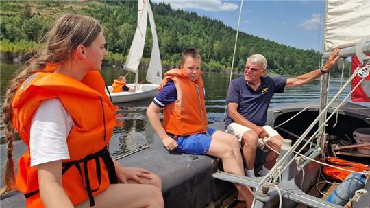 Der erfahrene Segler Lothar König zeigt Sophie und Noah, worauf es in der Jolle ankommt.