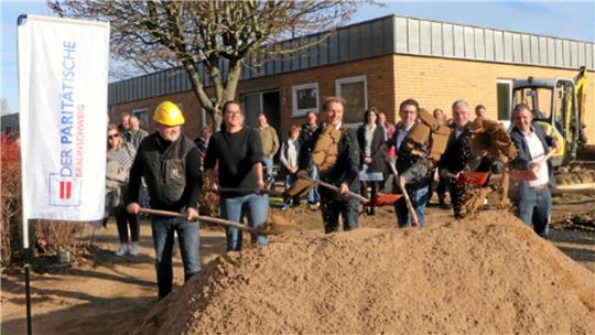Dzewad Delic, Geschäftsführer des beauftragten Bauunternehmens, Einrichtungsleiterin Anke Nickel, Architekt Sandi Morese, Hornburgs Ortsbürgermeister Marc Samel, Sven Spier, Geschäftsführer des Paritätischen Braunschweig, und Schladen-Werlas Bürgermeister Martin Schulze stehen mit Spaten vor einem Sandhaufen und schippen den Sand symbolisch für den ersten Spatenstich auf den Haufen vor ihnen.
