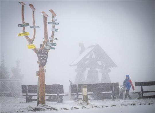 Der mit einer leichten Schneeschicht bedeckte 1215 Meter hohe Fichtelberg liegt im Nebel.