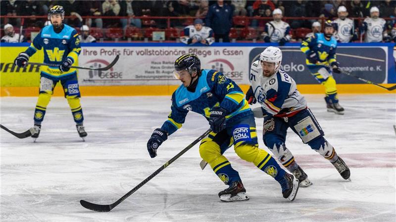 Eishockeyspieler in blauen und gelben Trikots kämpfen um den Puck auf dem Eis vor Zuschauern in der Halle