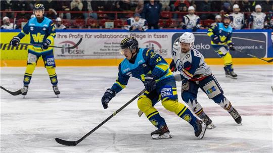 Eishockeyspieler in blauen und gelben Trikots kämpfen um den Puck auf dem Eis vor Zuschauern in der Halle