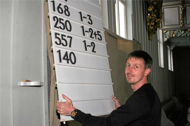 Der neue Küster Daniel Pätzolt ist mit vielen Aufgaben vertraut: Dazu gehört auch, die Tafel mit den zu singenden Kirchenliedern zu versehen.  Fotos: Nixdorf