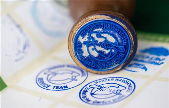 Der neue Stempel der Harzer Wandernadel ist vor einem Wanderpass zu sehen.