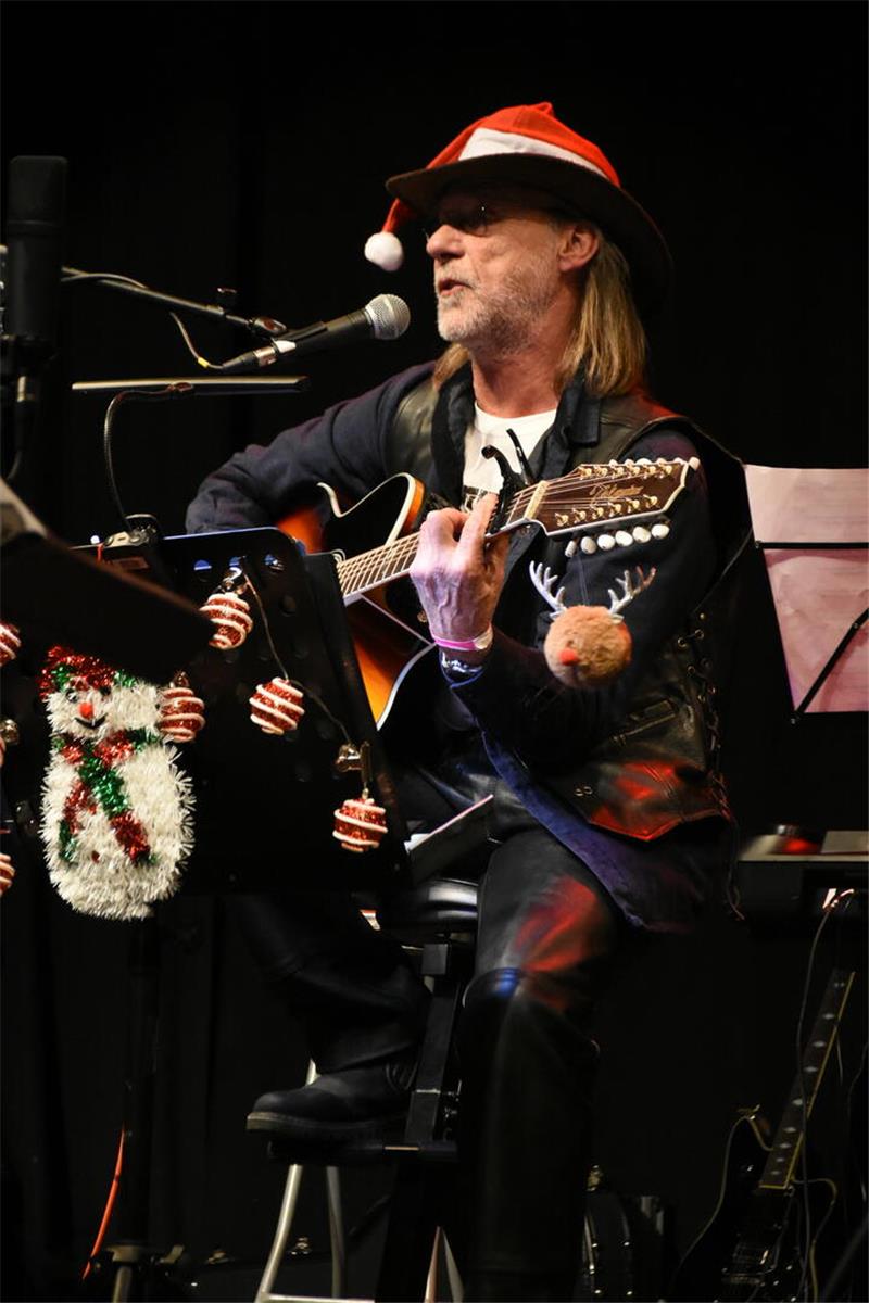 Ein Mann mit Hut hat eine Gitarre auf dem Schoß.