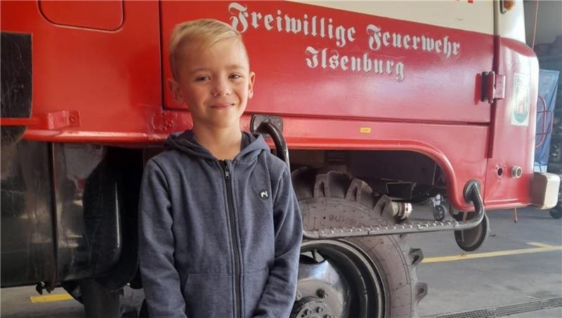 Ein Junge steht vor einem Feuerwehrauto.