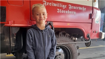 Ein Junge steht vor einem Feuerwehrauto.