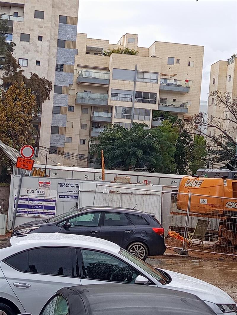 Parkende Autos vor einer Baustelle und einem Hochhaus in Raanana in Israel.