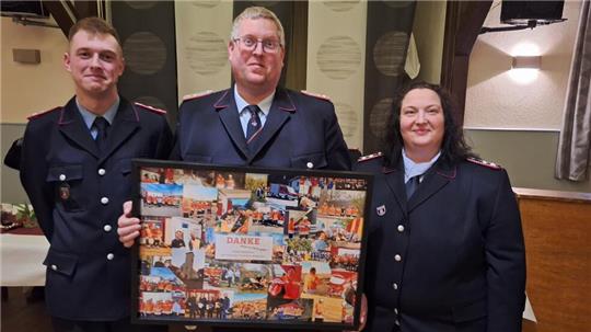 Der stellvertretende Gemeindebrandmeister Peter Bartels erhält ein Geschenk, weil er sich besonders für die Neubesetzung der Ortsbrandmeisterstelle eingesetzt hat. Nadine Brunke (r.) bekleidet nun diesen Posten.