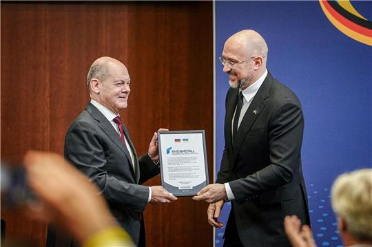 Der ukrainische Premierminister Denys Schmyhal überreicht Bundeskanzler Olaf Scholz beim 6. Deutsch-Ukrainischen Businessforum der DIHK ein Zertifikat für die Rheinmetall Joint-Venture Registrierung für die Ukraine.