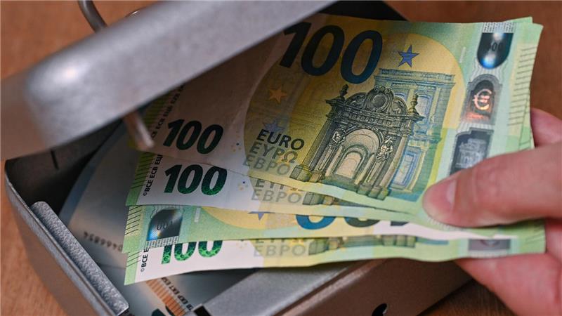 Eine Frau holt Eurobanknoten aus einer kleinen Geldkassette.