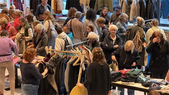 Das Foto zeigt viele Frauen zwischen Kleiderständern.