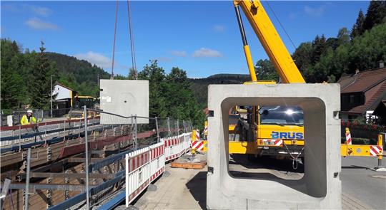Die 14 Tonnen schweren Rahmenbauteile mit einer lichten Weite von rund zwei mal zwei Metern werden mit einem Kran in die Baugrube gehoben. Insgesamt zehn Teile wurden jeweils mit einem Lkw angeliefert. Foto: Neddermeier