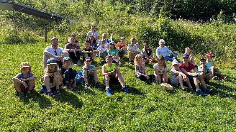 Braunlage: Ehrenamtliche kümmern sich eine Woche lang um Kinder Die 17 Kinder und Betreuer der Aktionen während der großen Ferien in St. Andreasberg nehmen entspannt auf einer Wiese am Matthias-Schmidt-Berg Platz.