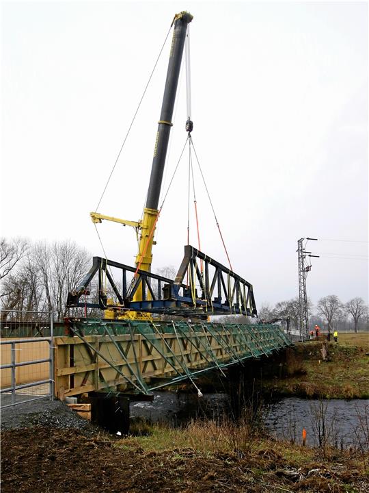 Die 60 Tonnen schwere Eisenbrücke schwebt ans westliche Oker-Ufer. Dort wird sie nun zerlegt und abtransportiert. Foto: Epping