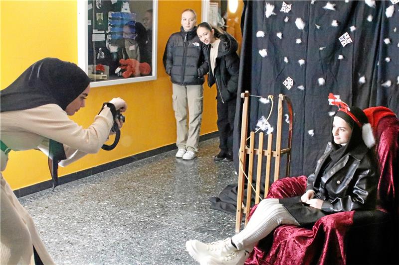 Kinder verkaufen Rentierköttel beim Adventsbasar im Oberharz Die 9d errichtet im orangefarbenen Flur eine Fotobox: Rayan macht das Bild und Zahraa nimmt in winterlicher Kulisse Platz.