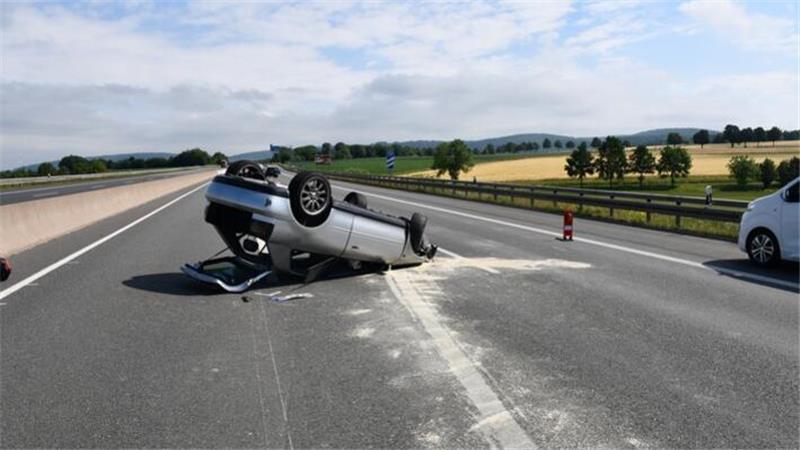 Ein völlig beschädigter Pkw liegt auf dem Dach auf einer Straße.