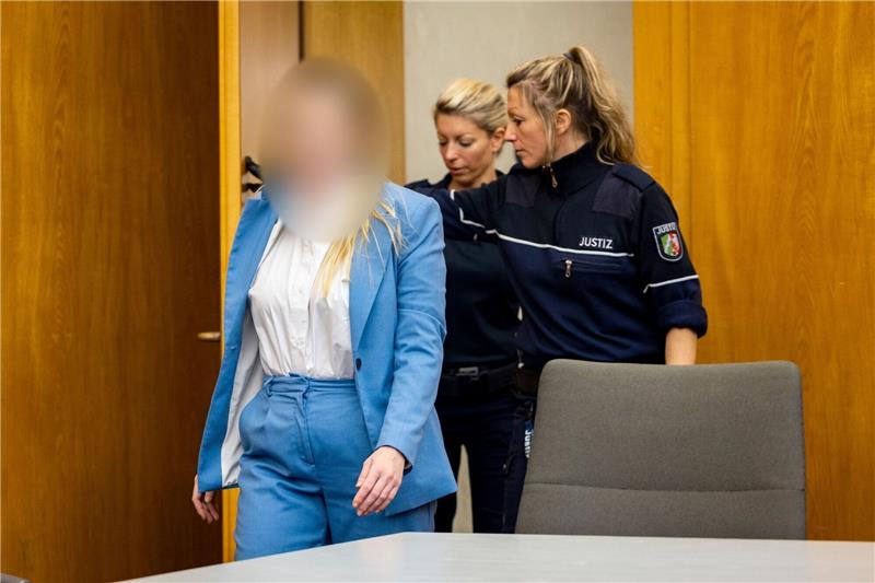 „Gift-Milchshake” für die Oma: Enkelin vor Gericht Die Angeklagte wird von zwei Justizbeamtinnen in den Gerichtssaal gebracht.