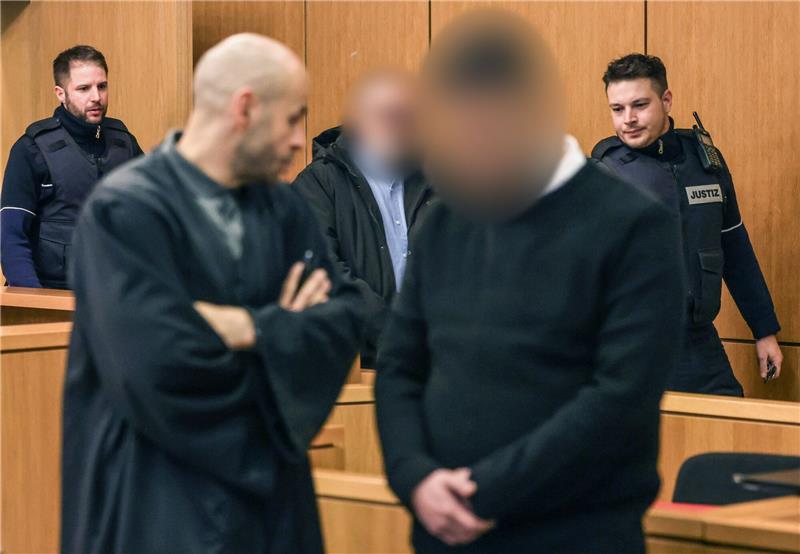 Explosion im Modegeschäft - Vater und Sohn vor Gericht Die Angeklagten werden von Justizbeamten in den Gerichtssaal geführt.