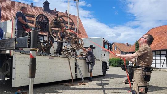 Ein schweres Maschinenteil wird per Kran von einem Lastwagen gehievt.