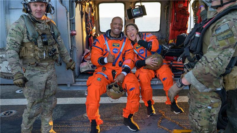 Die Astronauten Victor Glover und Christina Koch sitzen auf einem Hubschrauber der Navy auf dem Flugdeck des Schiffs USS John P. Murtha, nachdem sie aus ihrem „Orion“-Raumschiff geholt wurden.