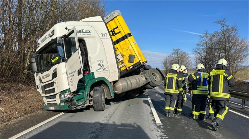 Feuerwehrmänner stehen an der Unfallstelle, ein Lkw ist auf die Seite gekippt