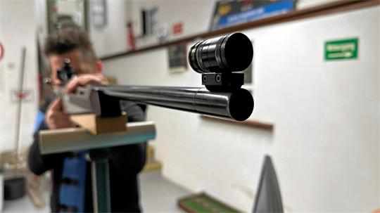 Das Bild zeigt einen Mann, der mit einem Sportgewehr zielt. 