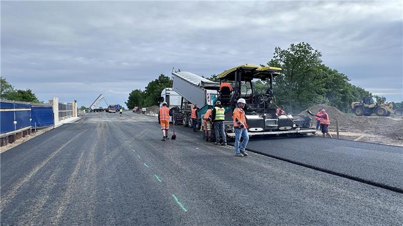 Die Bauarbeiter tragen die letzte Deckschicht auf.