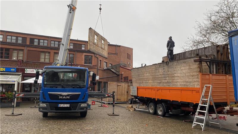 Ein Kran hebt die Bauteile für die Almhütte an ihren Platz auf dem Jacobsonplatz.