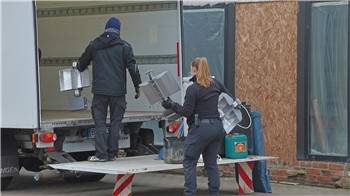 Die Beamten tragen mehrere Geräte und Säcke aus dem betroffenen Gebäude.