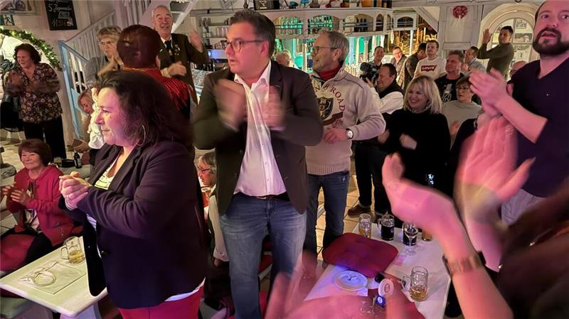 Die Besucher der Feier, meist Freunde, Kollegen und Weggefährten, stehen auf den Bänken und applaudieren zum Takt der Musik.