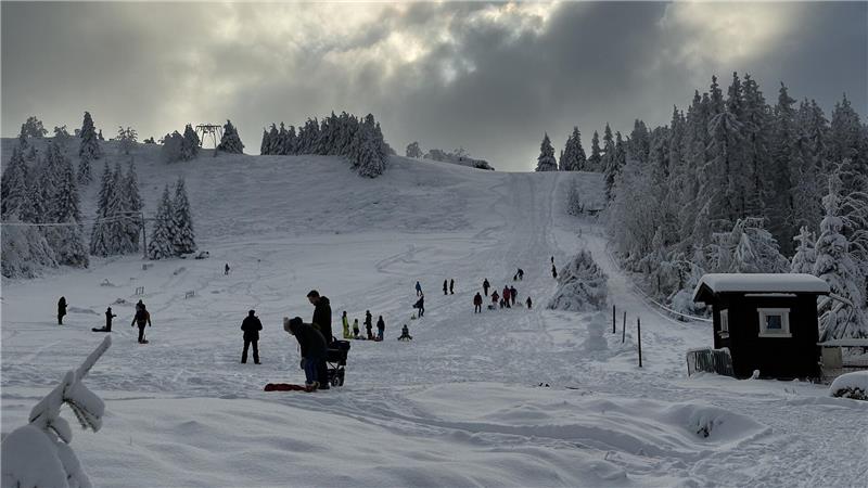 Das Bild zeigt Wintersportler vor dem verschneiten Skihang in Sonnenberg.