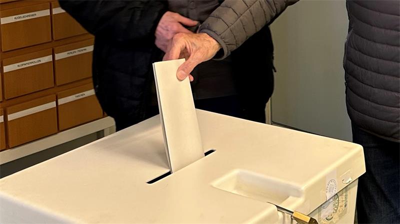 Das Foto zeigt die Hand eines Mannes, der seinen Wahlzettel in eine Urne steckt.