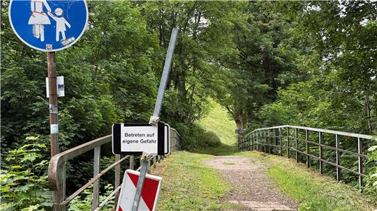 Das Foto zeigt eine Brücke mit Schildern und Geländer.