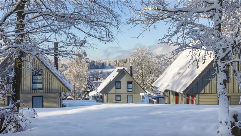 Zu sehen sind drei Häuser in einer verschneiten Landschaft.