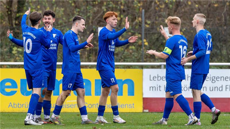 Goslarer SC 08 erkämpft sich Sieg über Salder Sechs Fußballspieler in blauen Trikots mit weißen Nummern stehen auf dem Spielfeld und geben sich gegenseitig High-Fives.