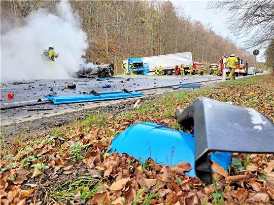 Die Fahrbahn der Bundesstraße 4 gleicht einem Trümmerfeld: Feuerwehrleute sind dabei, den brennenden Pkw zu löschen. Wer am Steuer gesessen hat oder ob womöglich sogar noch weitere Personen in dem Fahrzeug saßen, muss noch ermittelt werden. Foto: Exner