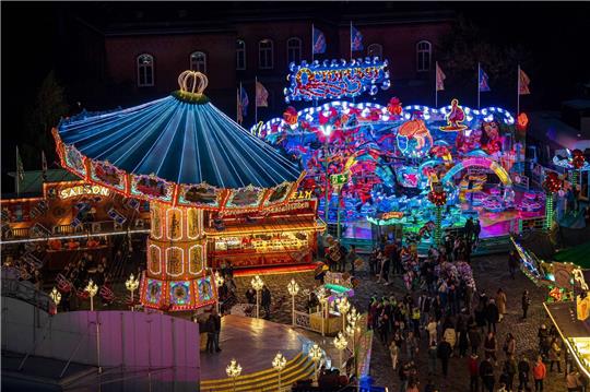 Die Fahrgeschäfte auf dem Freimarkt leuchten mit bunten Lichtern und Reklameschriftzügen.