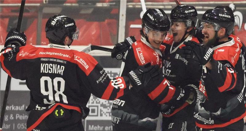 Fünf Eishockeyspieler in schwarzen Trikots jubeln.