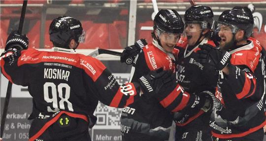 Fünf Eishockeyspieler in schwarzen Trikots jubeln.