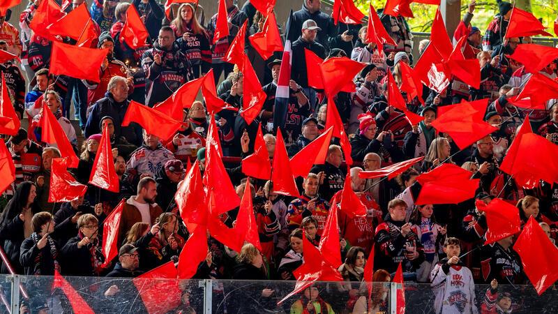 Menschenmenge in einem Stadion, die zahlreiche rote Fahnen schwenkt