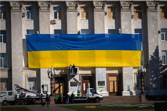 Die Fassade eines Verwaltungsgebäudes in der ukrainischen Stadt Cherson wird mit einer riesigen Nationalfahne geschmückt.
