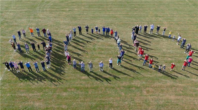 Die Festbesucher formieren auf dem Upener Sportplatz anlässlich des Jubiläums eine 900.
