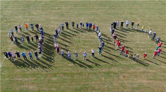 Die Festbesucher formieren auf dem Upener Sportplatz anlässlich des Jubiläums eine 900.