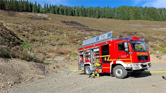 Feuerwehrauto vor Heidefläche.
