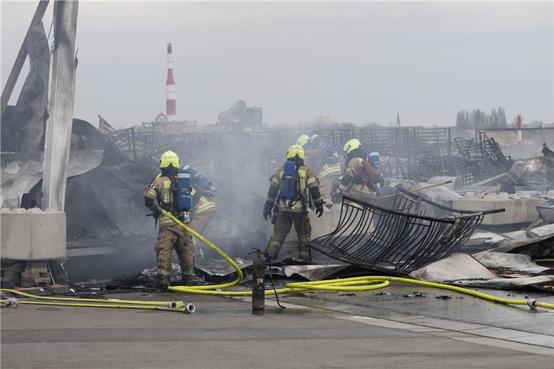 Brand in Berliner Flüchtlingsunterkunft: Neue Erkenntnisse Die Feuerwehr löscht die Brandstelle bei der Flüchtlingsunterkunft am ehemaligen Flughafen Tegel. Die Nachlöscharbeiten sind inzwischen abgeschlossen.