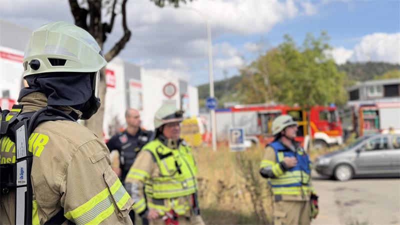 Feuerwehrleute in Schutzkleidung und Helmen stehen vor einem Einsatzfahrzeug im Freien
