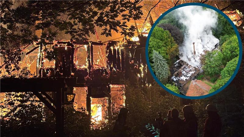 Zusehen sind zwei Feuerwehrmänner in voller Montur, die auf ein brennendes Gebäude schauen.