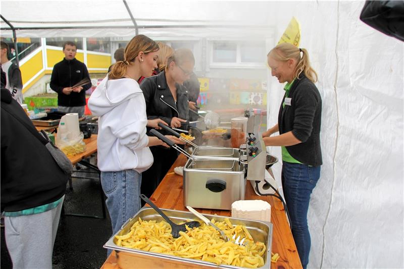 Die Fritteuse dampft und läuft auf Hochtouren: Die selbstgemachten Pommes sind der Renner. Aber auch das Kürbisschnitzen (kleines Bild) kommt gut an. Foto: Jenzora