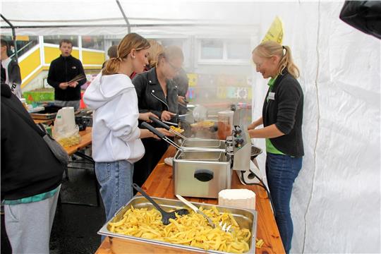 Die Fritteuse dampft und läuft auf Hochtouren: Die selbstgemachten Pommes sind der Renner. Aber auch das Kürbisschnitzen (kleines Bild) kommt gut an. Foto: Jenzora